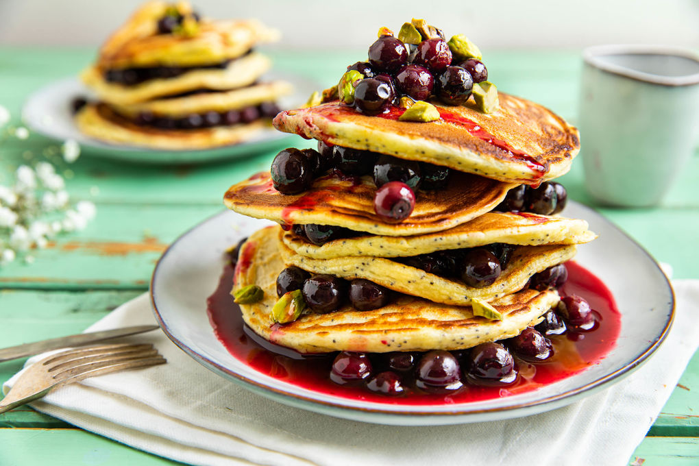 Ricotta-Zitronen-Pancakes mit Mohn, dazu Blaubeersauce und Pistazien